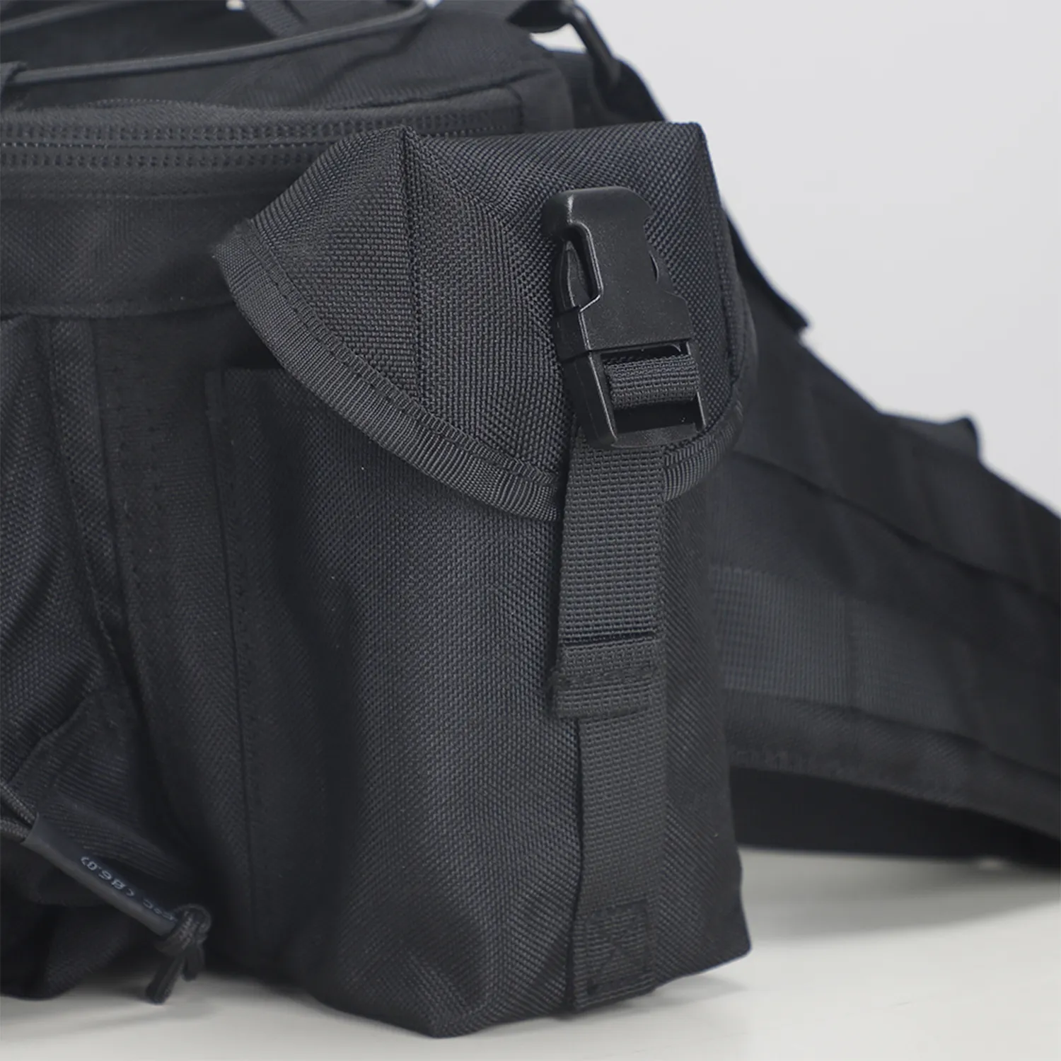 Side pouch detail on black tactical waist bag with flap closure