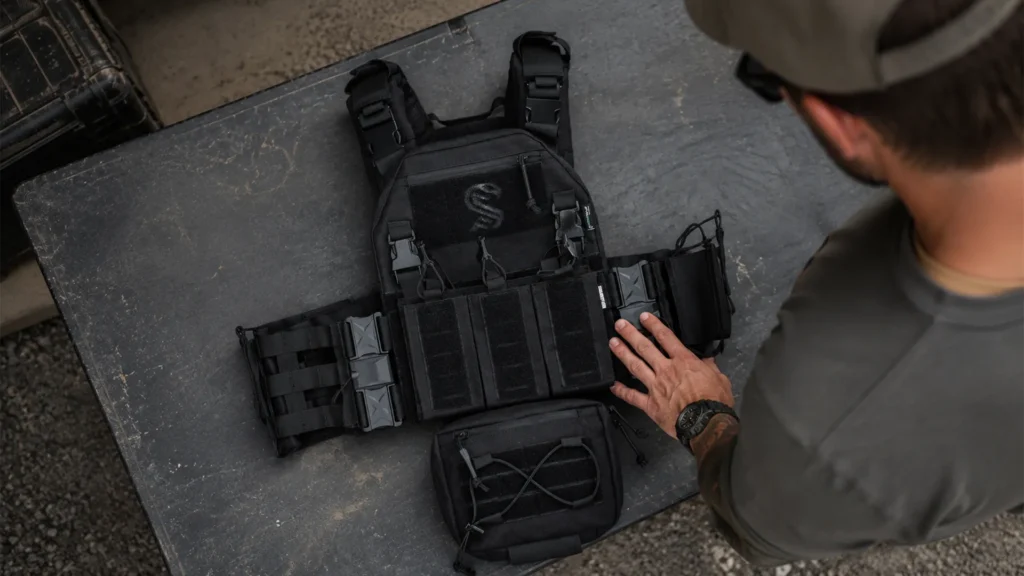 Quick Release Cummerbund installed on black plate carrier during gear setup on outdoor training table